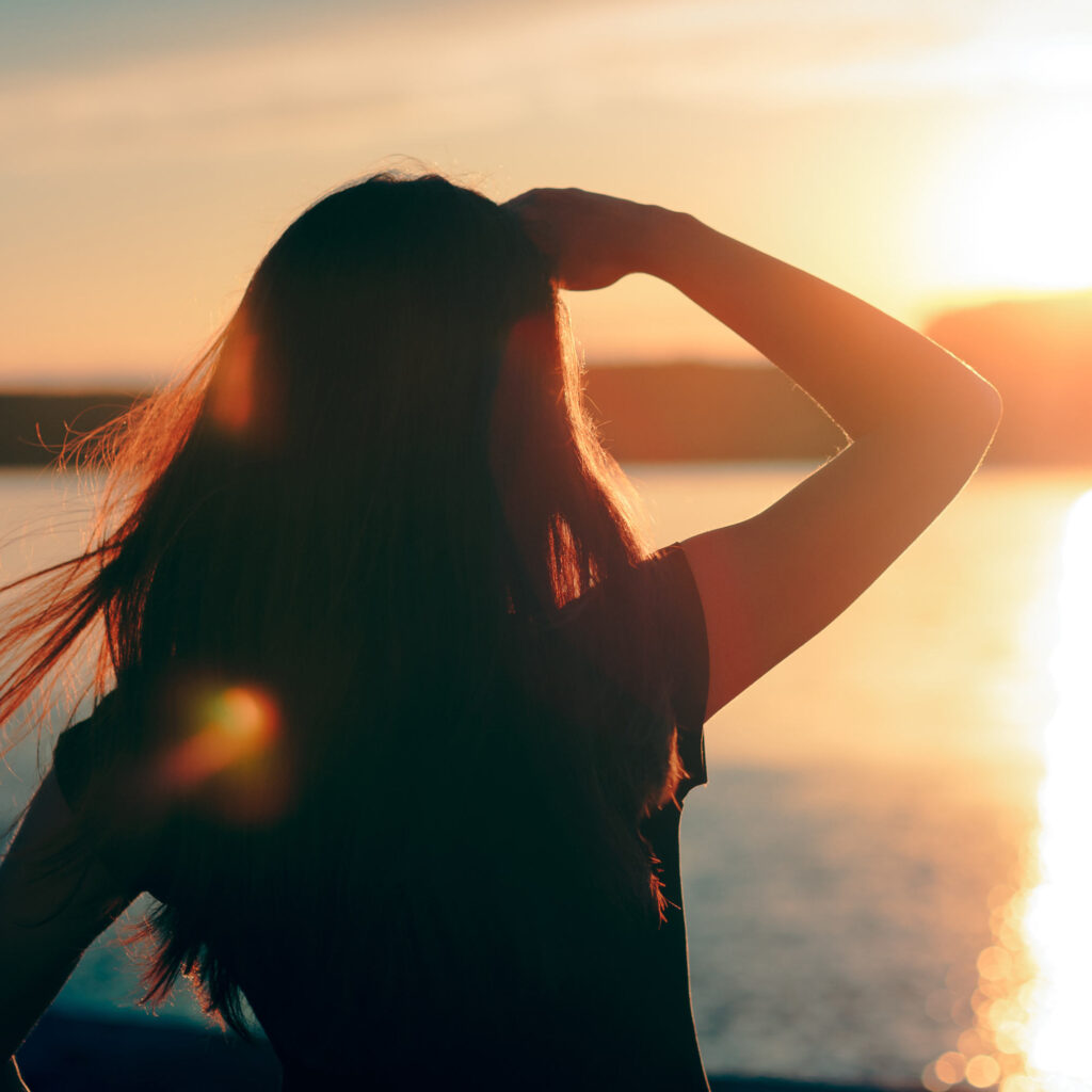 emme regardant vers l’horizon sous un soleil levant, symbolisant l’espoir et l’avenir